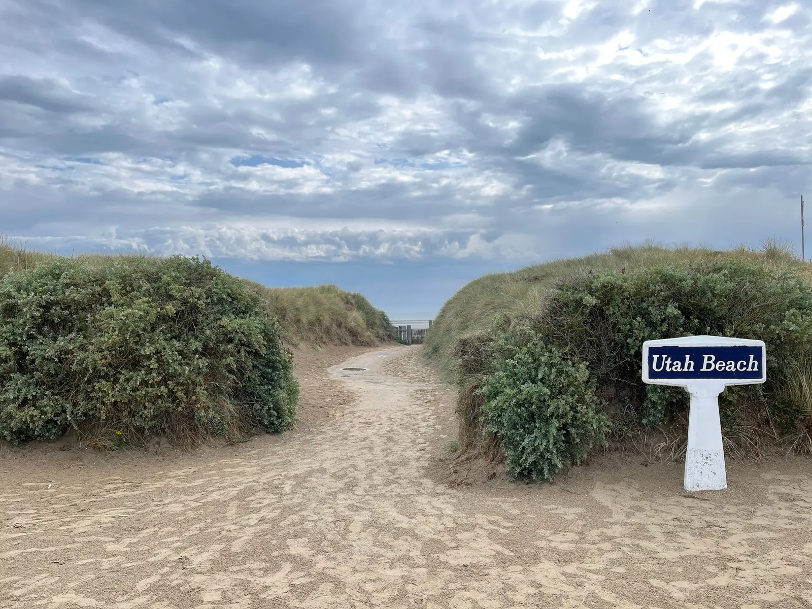 A sandy path through dune grass leading from the Utah Beach museum down to the shoreline.