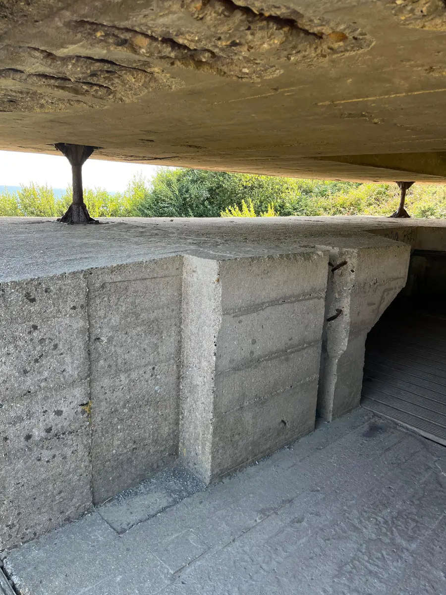The interior of a German concrete observation post, looking out through a horizontal viewing slit to the sea.