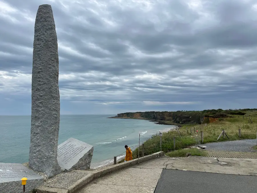 A granite pylon memorial standing on top of a German bunker at Pointe du Hoc.