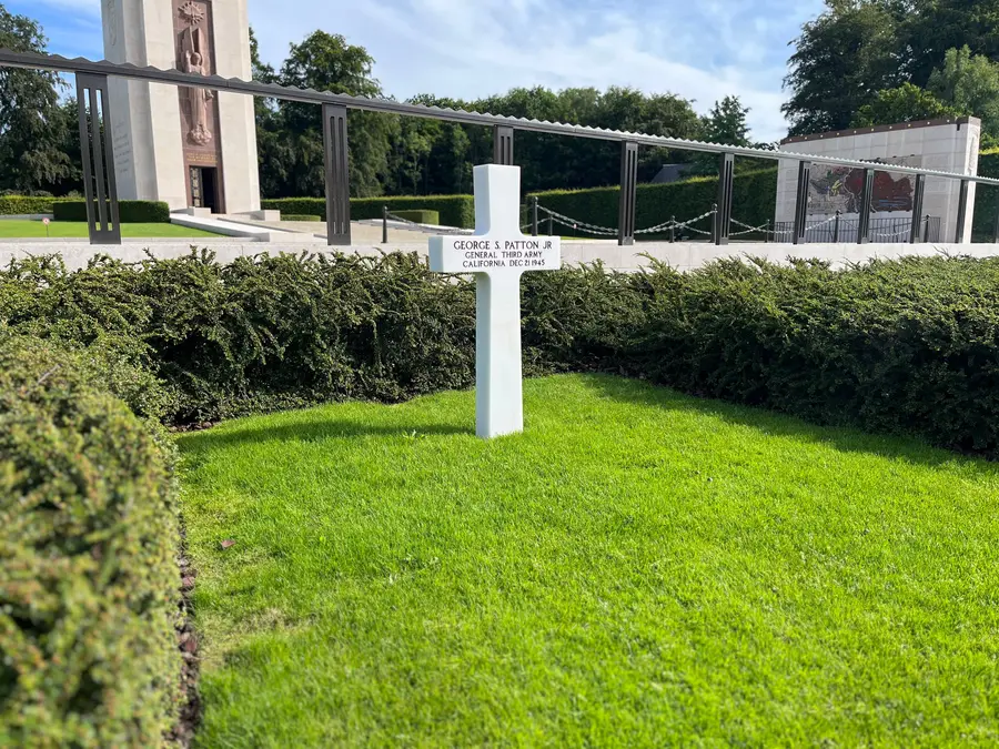 A single white marble cross inscribed George S. Patton Jr., standing apart at the head of the graves.